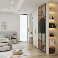 Dressing moderne de luxe sur mesure avec porte vitrée, mobilier blanc, lustre et ensemble d'organisation pour îlot central