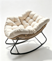 Fauteuil à bascule moderne en rotin tressé, capitonné avec boutons, coussin épais beige, structure en métal noir, coque incurvée surdimensionnée pour salon
