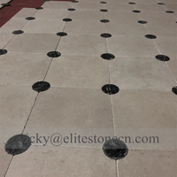 Carrelage de sol en pierre calcaire beige avec points noirs en forme d'échiquier