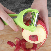 Multifunctionele handmatige plastic aardappel- en groenteschiller met roestvrijstalen mes, rood/groen, huishoudelijk gebruik.