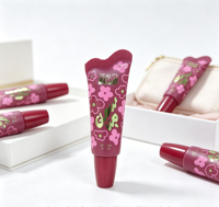Tube souple pour gloss à lèvres imprimé floral personnalisé, bord ondulé scellé, embout transparent incurvé et incliné, capuchon conique rouge bordeaux, mini soin des lèvres à l'huile