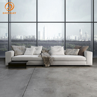 Canapé blanc moderne à profil bas, sectionnel en cuir minimaliste avec accoudoirs carrés et base au sol, idéal pour appartement de luxe en immeuble de grande hauteur