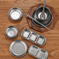 Ensemble de vaisselle rétro en acier inoxydable comprenant des bols, des assiettes, des tasses, des baguettes, des cuillères et des assiettes rectangulaires.