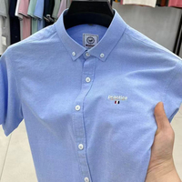 Kemeja Pria Lengan Pendek Biru Muda, Model Kasual Oxford Kancing Depan dengan Bordir Kecil Gaya Minimalis