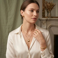 Parure de bijoux hypoallergénique en acier inoxydable plaqué or, comprenant un collier double coquille, des boucles d'oreilles puces et un bracelet ajustable à ouverture.