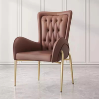 Fauteuil moderne de luxe capitonné en cuir avec dossier haut et pieds en métal doré pour salle à manger