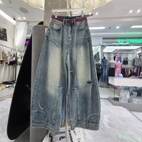 Nouvelles collections automne 2026 : Jean scimitar en denim bleu délavé pour femme, taille haute, coupe ample, jambe large, déchiré, style décontracté chic pour le quotidien.