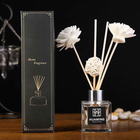 Diffuseur de parfum d'ambiance en verre carré transparent avec logo personnalisé, bouchon argenté, boule de rotin naturel et fleur de Sola blanche – Décoration et cadeau pour la maison