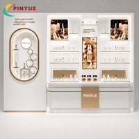 Comptoir de présentation de luxe en or blanc pour produits de soin et parfums, avec étagères LED ovales lumineuses et vitrines en verre pour l'image de marque de détail de produits de beauté