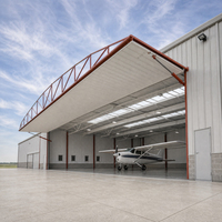Hangar pour avions légers avec auvent rétractable, baie de service ouverte, porte latérale et accès par aile de dégagement en béton