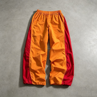 Pantalon de survêtement homme coupe large et ample, couleur rouge orangé avec blocs de couleur et bande latérale, taille élastique, en nylon coupe-vent, style streetwear et skate