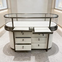 Vitrine de luxe circulaire en forme de tour, base en cuir crème, garniture dorée, verre incurvé, éclairage LED, niche murale, présentoir pour bijouterie