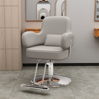 Fauteuil de salon en cuir PU gris avec structure en acier inoxydable poli, accoudoirs rembourrés, coussin lombaire, repose-pieds et base pivotante à 360°