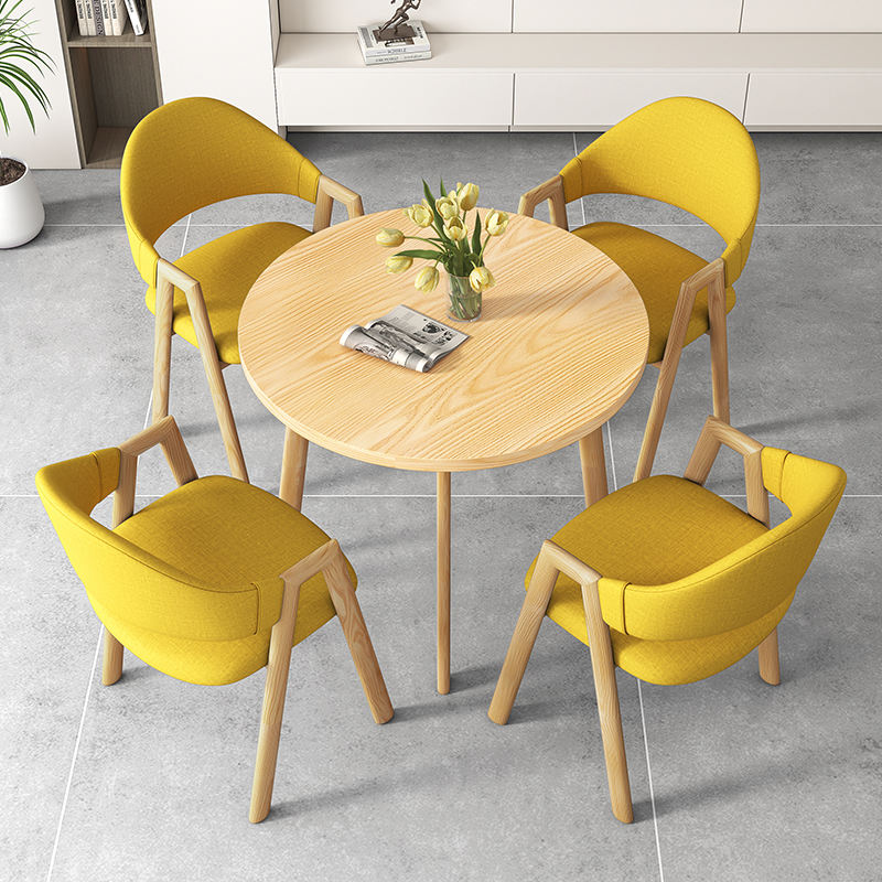 Une table et quatre chaises en couleur bois (chaises en tissu jaune)