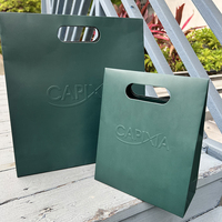 Sac cadeau en papier mat laminé vert foncé avec logo en relief découpé et couvercle plat, fourni par le fabricant