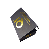 Boîte cadeau personnalisée de style livre bleu marine avec un marquage en feuille d'or et un profil fin pour offrir des vêtements et des accessoires