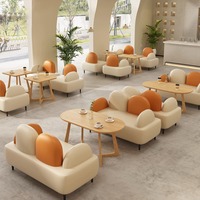 Canapé deux places minimaliste crème et orange avec dossier coussiné, table ovale en bois et table d'appoint ronde pour café et salon
