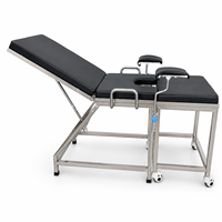 Table d'examen gynécologique en acier inoxydable pour centre médical avec supports de jambes rembourrés et structure stable