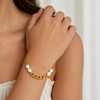 Bracelet chaîne gourmette en acier doré architectural avec quatre perles baroques, maillons épais connectés à un câble fin, fermoir réglable pour femme