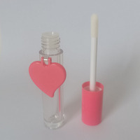 Tubo cilíndrico para brillo labial con tapa en espiral, etiqueta en forma de corazón rosa, material plástico