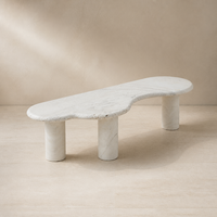 Table basse moderne en travertin beige naturel de forme organique Wabi Sabi, avec 3 pieds cylindriques incurvés irréguliers, finition mate en pierre