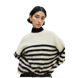 Belle femme modélisant un pull douillet et surdimensionné en fourrure avec des rayures noires audacieuses sur un col roulé noir. - Product Image 1
