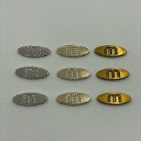 Étiquettes métalliques personnalisées ovales en strass anti-corrosion avec logo lettre M, vente en gros pour vêtements, sous-vêtements, sacs, casquettes