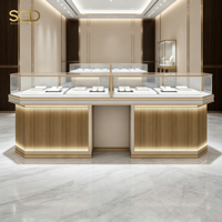 Vitrine à bijoux de luxe avec cadre doré, verre ultra-transparent, éclairage LED chaud et rangement dissimulé pour magasin de détail haut de gamme