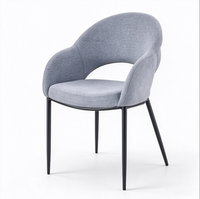 Fauteuil moderne en tissu gris clair avec dossier découpé unique et pieds en métal noir pour salon ou salle à manger