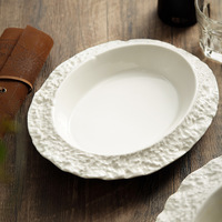 Assiette à salade en porcelaine céramique texturée de luxe, forme ovale irrégulière, bord en relief blanc, style minimaliste moderne, compatible micro-ondes