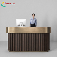 Bureau d'accueil moderne blanc cannelé avec finition or champagne, silhouette incurvée, base encastrée et design minimaliste pour hall d'entreprise ou magasin