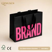 Sac shopping en papier noir mat personnalisé OEM, surdimensionné, avec lettrage de marque et larges poignées en ruban de satin pour boutique de détail