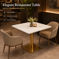 Table et chaises de restaurant, plateau carré en pierre frittée avec base cylindrique dorée et fauteuils beiges à accoudoirs en forme de baril pour café-bar