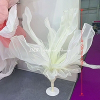 Grande fleur géante en tissu organza blanc, sur pied, pour la décoration d'allées de mariage et de scènes.