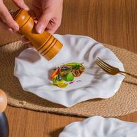 Assiette de service en céramique froissée artistique, design à bord ondulé irrégulier pour la restauration fine et la présentation artistique