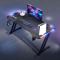 Escritorio Gamer Ergonómico RGB LED al por Mayor con Portavasos, Estructura Robusta en Forma de Z, Mesa de Computadora de Metal, Superficie de Fibra de Carbono, Estilo Moderno para Estudio