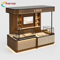Kiosque de présentation de bijoux vert sauge et or avec panneaux cannelés, éclairage LED et comptoirs vitrine arqués pour stands de boutiques en centre commercial