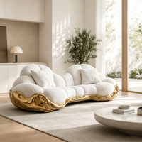 Canapé multiplace incurvé en bouclette blanche avec base en fibre de verre sculptée dorée et table basse ronde en pierre pour salon de luxe
