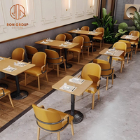 Ensemble de meubles modernes pour café, restaurant, salon de thé : canapés incurvés verts, tables rondes en bois et chaises oranges