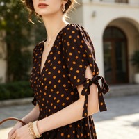 Robe midi à pois à col en V, boutonnée sur le devant, avec poignets à nouer, manches courtes et taille empire, idéale pour le quotidien, les voyages et les rendez-vous café. Personnalisation disponible.