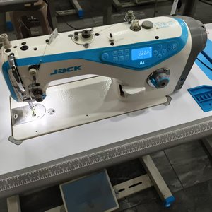 Machine à coudre industrielle JACK d'occasion, informatisée, à point noué, à lit plat, à entraînement direct, avec moteur d'occasion pour la production de vêtements - Product Image 1