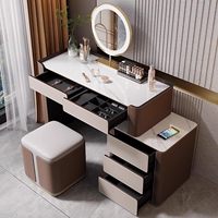 Coiffeuse moderne de luxe avec plateau en dalle de roche et tiroirs à bijoux en velours, miroir LED et tabouret en cuir technologique pour chambre à coucher.