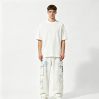 Jean cargo blanc à jambe large, délavé effet éclaboussures de peinture bleue, avec bords de poche effilochés, détails déchirés, décorations patchwork, coupe ample, style streetwear en denim
