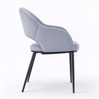 Fauteuil moderne en tissu gris clair avec dossier découpé unique et pieds en métal noir pour salon ou salle à manger