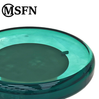 Table console moderne pour salons, avec plateau en acrylique translucide vert et base en acier inoxydable doré.