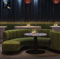 Canapé banquette capitonné en velours vert à cannelures courbes, table ronde à plateau en terrazzo bleu pour restaurant, bar à vin ou lounge aux tons sombres