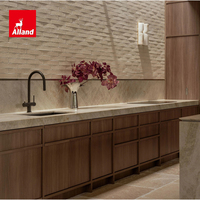 Cuisine intégrée Alland moderne de luxe, style côtier, avec armoires élégantes en noyer, vitrine à vin en verre courbé et îlot central