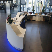 Bureau de réception incurvé personnalisé en Corian blanc avec base en acier inoxydable argenté pour hall d'hôtel