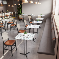 Chaises de salle à manger à dossier en cannage avec sièges rembourrés couleur caramel et tables en marbre avec base en piédestal noir pour café-bistro moderne