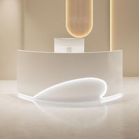 Comptoir de réception incurvé blanc crème, ovale irrégulier, avec éclairage LED encastré, finition mate, minimaliste, pour salon de beauté, sur mesure